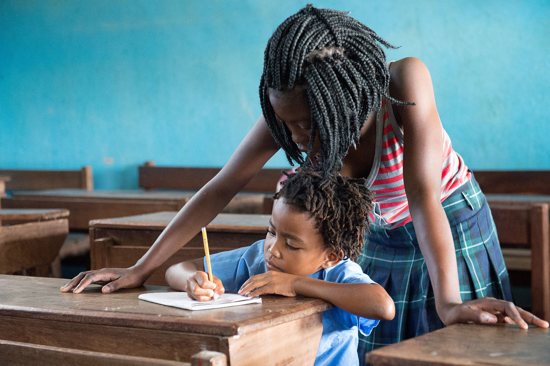 Eine Schülerin als Lehrerin - Flora Saraiva schaut einem jungen Mädchen in Mosambik zu, ob sie schon korrekt schreiben kann. 