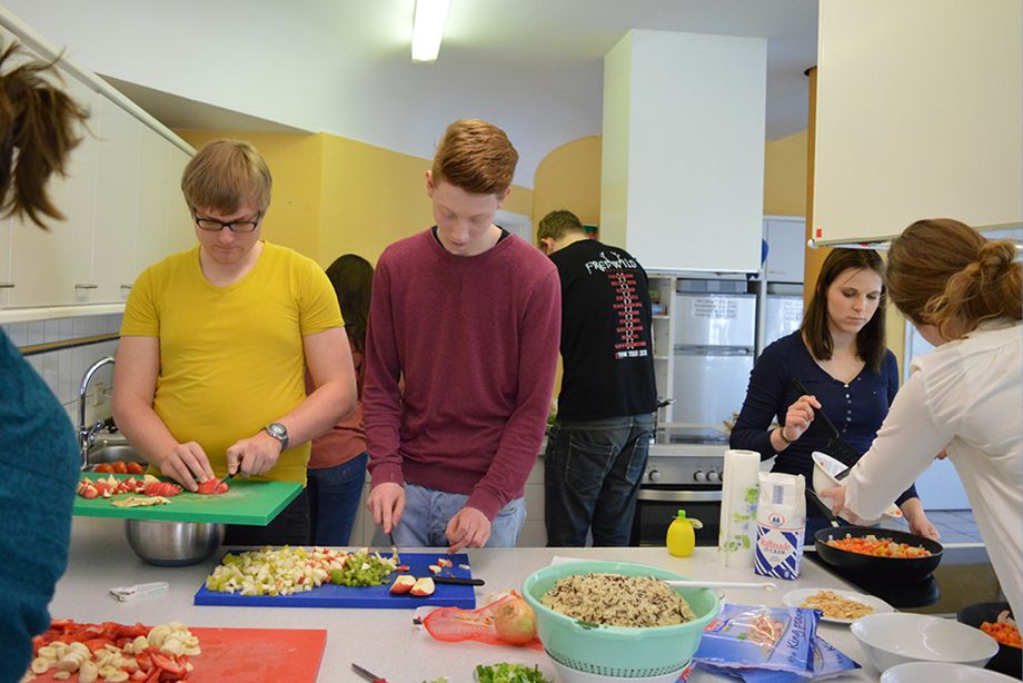 Junge Menschen schneiden Obst und Gemüse für das Seminar "Gesunde Ernährung".
