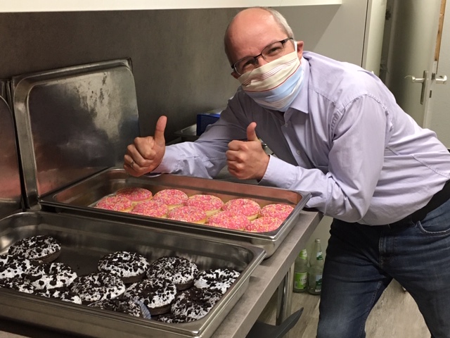 Ein Mitarbeiter von Friedehorst freut sich über die Donuts und zeigt mit den Daumen nach oben.